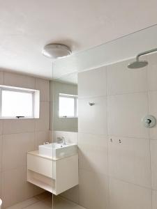 a white bathroom with a sink and a mirror at Bunkers Inn Guesthouse in East London +33 photos