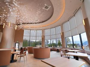 un restaurante con mesas, sillas y ventanas grandes en Lake Toya Tsuruga Resort HIKARINOUTA, en Lago Toya