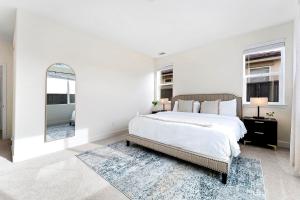 a white bedroom with a large bed and a mirror at Stylish 4BR Home Nr Golden Eagle Sports Complex in Sparks +32 photos
