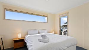 a bedroom with a large white bed with a window at Breck in Dinner Plain
