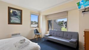 a bedroom with a bed and a couch and a window at Breck in Dinner Plain