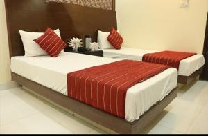 two beds with red and white pillows in a room at hotel Priya Palace BY BYOB Hotels in New Delhi