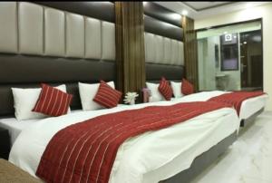 a bedroom with a large bed with red and white pillows at hotel Priya Palace BY BYOB Hotels in New Delhi