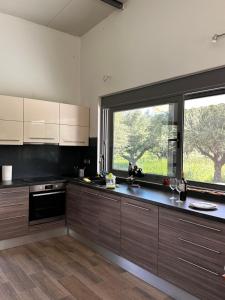 una cocina con armarios de madera y una gran ventana en Elaiocampus luxury house, en Kamáres