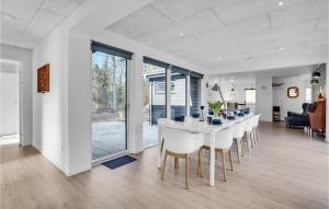 a kitchen and dining room with a white table and chairs at Nice Home In Frvang With Wifi, 5 Bedrooms And Outdoor Swimming Pool in Fårvang
