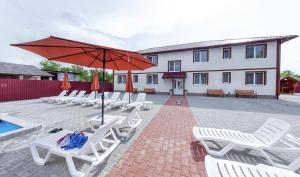 a group of lounge chairs and an umbrella and a pool at Ранчо Офре in Solotvyno