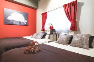 1 Schlafzimmer mit 2 Betten mit roten Wänden und einem Fenster in der Unterkunft Kuru Bentencho in Osaka