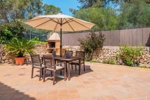 a wooden table with chairs and an umbrella at Villa Alma Azul in Llucmajor