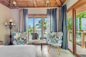 バガにあるThe Baga Beach Resortのベッドルーム1室(ベッド1台、椅子2脚、窓付)