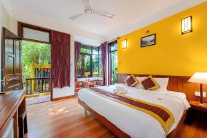 a bedroom with a large bed with a yellow wall at Hoi An Green Riverside Oasis Villa in Hoi An