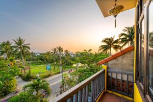 uma varanda com vista para uma rua e palmeiras em Hoi An Green Riverside Oasis Villa em Hoi An