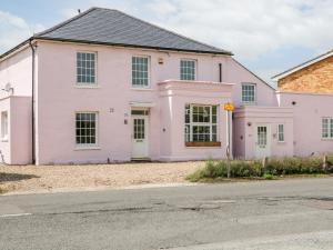 een roze huis aan de kant van een straat bij Burfield Cottage in Windsor