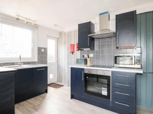 een keuken met blauwe kasten en een fornuis met oven bij Burfield Cottage in Windsor