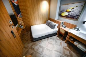 een kleine slaapkamer met een bed en een wastafel bij La Opera Saigon Hotel in Ho Chi Minh-stad
