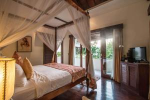 um quarto com uma cama de dossel e uma televisão em Luxury 3 BR Villa Seminyak Villa Kalimaya 3 em Seminyak