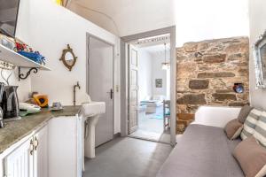 a kitchen with white counters and a stone wall at Apano Vrysi Tinos 3 in Tinos
