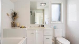 a white bathroom with a toilet and a sink at Krystal Peaks in Dinner Plain