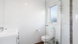 a white bathroom with a toilet and a shower at Krystal Peaks in Dinner Plain +5 photos