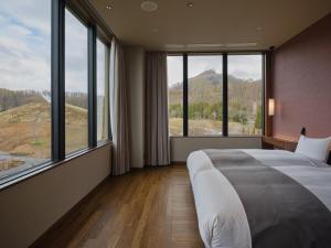 ein Schlafzimmer mit einem großen Bett und großen Fenstern in der Unterkunft Lake Toya Tsuruga Resort HIKARINOUTA in Tōya-See