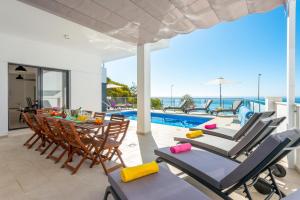 patio z krzesłami i stołem oraz basen w obiekcie Villa Ladera Sol by Villa Plus w mieście Nerja
