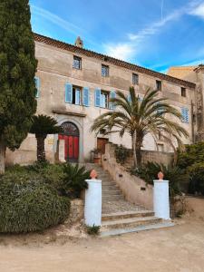 a building with stairs and palm trees in front of it at Hotel Palazzu Pigna in Pigna