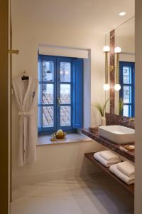een badkamer met een bad, een wastafel en een raam bij Orloff Legacy Suites Hydra in Hydra