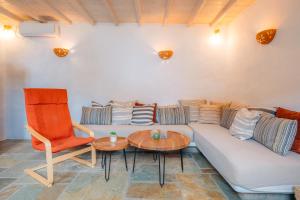 a living room with a couch and a table and a chair at Houses at Chrisopigi Sifnos in Chrisopigi