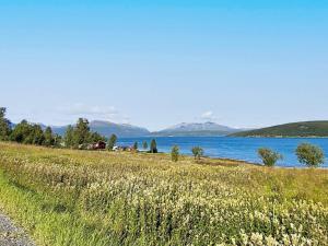 a field of grass next to a body of water at 7 person holiday home in Rossfjordstraumen in Straumen
