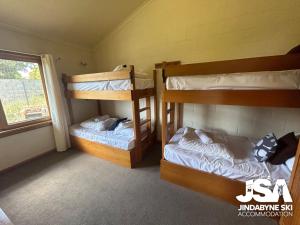 two bunk beds in a room with a window at Moonbah 2 in Jindabyne