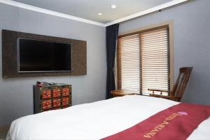 a bedroom with a bed and a flat screen tv at Ariana Hotel in Daegu