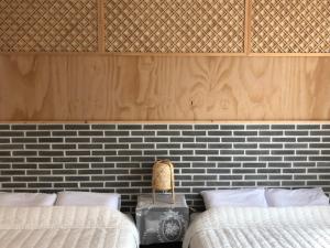 a bedroom with two beds and a brick wall at Cheukhu-dong 19street Guesthouse in Mokpo