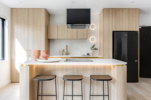 a kitchen with a counter with stools and a refrigerator at Kahlo Bondi - Luxury Escape - 2 Bedroom Furnished Apartments in Sydney