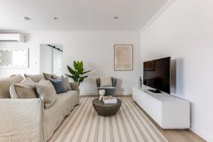 a white living room with a couch and a tv at Kahlo Bondi - Luxury Escape - 2 Bedroom Furnished Apartments in Sydney