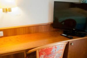 a wooden desk with a television and a chair at Hotel Stadt Steinbach in Steinbach im Taunus