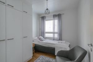 een kleine slaapkamer met een bed en een stoel bij Kotimaailma Joensuu - Saunallinen kolmio keskustassa in Joensuu
