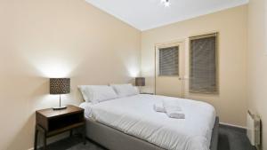a white bedroom with a bed and a night stand at Prosecco in Dinner Plain