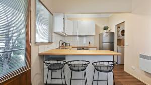a kitchen with three bar stools and a counter at Prosecco in Dinner Plain