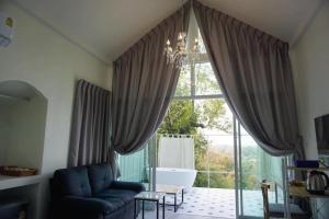a living room with a couch and a large window at La Maison Blanche Chiang Rai Resort in Chiang Rai