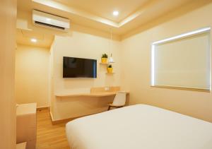 a bedroom with a bed and a desk and a tv at Bloom Hotel Koramangala in Bangalore