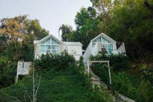 a house on top of a hill with trees at La Maison Blanche Chiang Rai Resort in Chiang Rai
