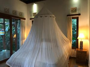 un letto con zanzariera bianca in una camera di Cozy Wayan Sueta's Garden Villa 2 ad Ubud