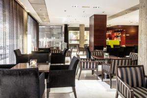un ristorante con sedie nere, tavoli e finestre di Zenit Don Yo a Saragozza