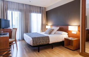 Habitación de hotel con cama, escritorio y TV. en Zenit Don Yo, en Zaragoza