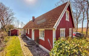 una casa roja y blanca con un coche aparcado al lado en Amazing Home In Bstad With House A Panoramic View, en Båstad