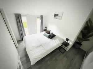 a white bedroom with a bed and a window at Beachhouse Veluwemeer mit großem Garten in Strandnähe (inkl. Hallenbadnutzung) in Hulshorst +30 photos