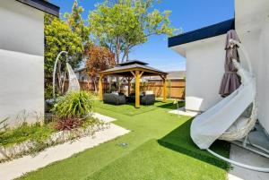 einen Hinterhof mit einer Hängematte und einem Pavillon in der Unterkunft Pearl Beach Villa Huntington Beach in Huntington Beach