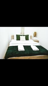 duże łóżko z zieloną i białą pościelą i poduszkami w obiekcie Brasov Accomodation1 w Braszowie