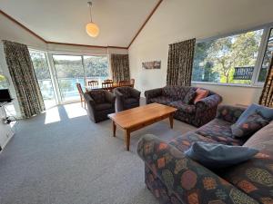 a living room with couches and a table and windows at Banksia 1 in Jindabyne