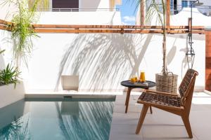 Mariann Premium Suites في لاردوس: فناء مع طاولة وكرسي بجوار حمام سباحة