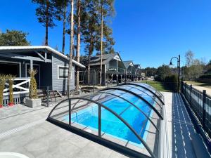 a swimming pool with a glass bridge next to a house at Domki Albertówka - Strefa Relaksu in Ostrowo